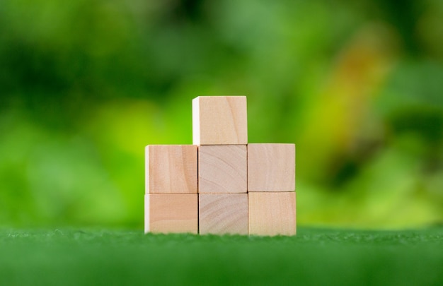 Stacking blank wooden cubes on green background with copy space for input wording and infographic icon Empty brown wooden object block for symbol icon put technology zero gravity business concept