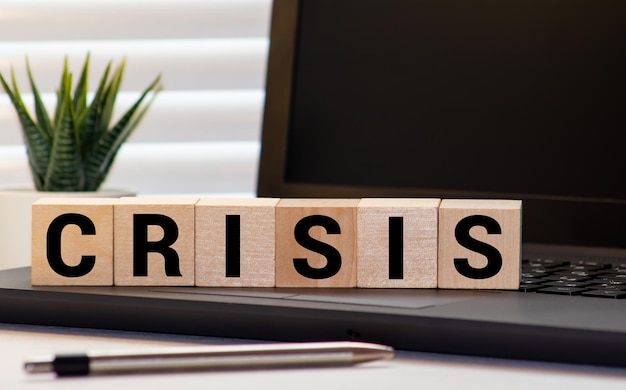 Photo stacking coins and wooden block with word crisis economy and financial crisis concept