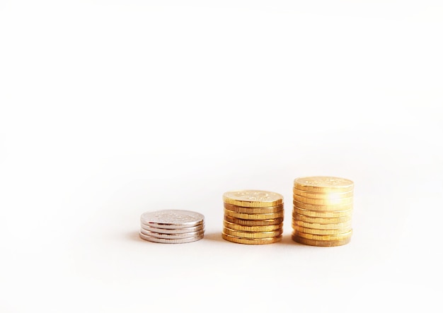 Stacks of coins increasing in height, on a white studio background, side view