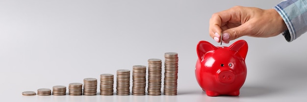 Stacks of rising financial coins and piggy bank person throws coin investment and money savings