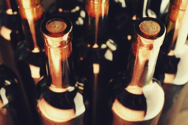 Stacks of wine bottles on wooden background upside view Close up