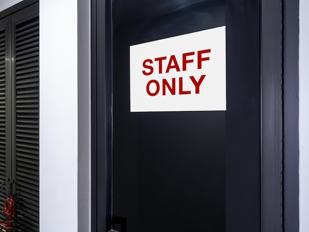 Staff only area notice sign Text STAFF ONLY sticker notification sign on dark glass door in white building Gate for staff who authorized person working in this place