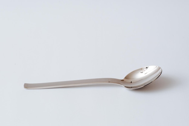 Stainless steel teaspoon on white background kitchenware copy space closeup