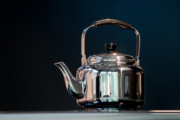 Stainless Water Crow or Vintage Kettle tea pot on electronic stove in modern dark blue background