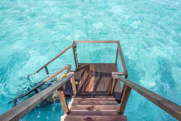 Stair down to crystal clear ocean from water villa private balcony