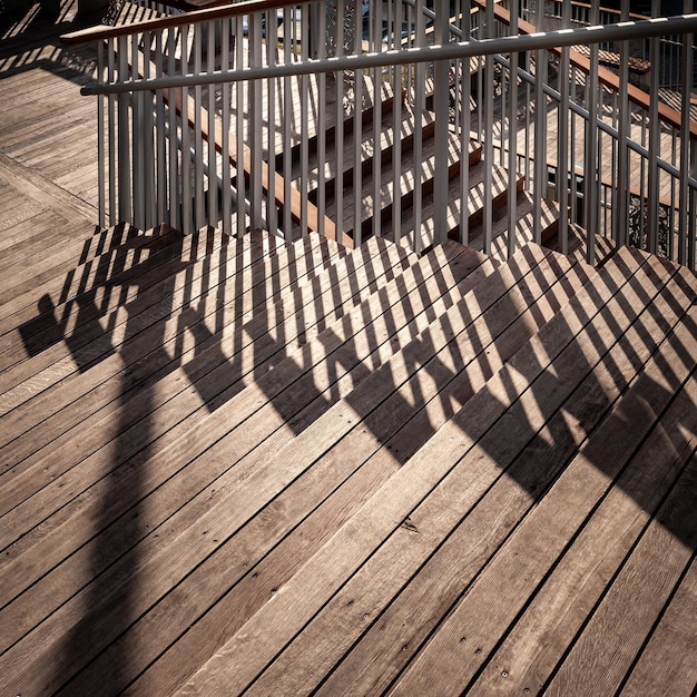 Staircase with a shadow from the railing Closeup of a staircase descending with wooden steps