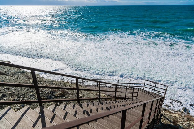 The stairs descend to the shingle beach to the stormy sea On the sea big waves with foam