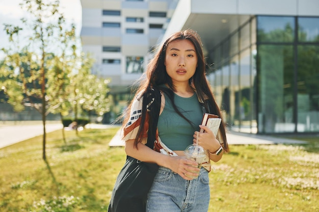 Standing against modern building Young asian woman is outdoors at daytime