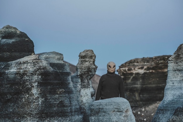 Standing alien mask people in moon style landscape Concept of diversity and alien invasion Portrait of extraterrestrial life One ufo standing and looking around Blue mood night color