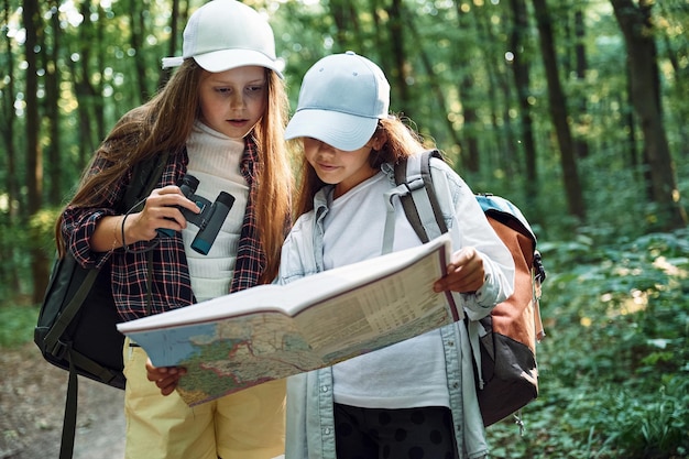 Photo standing on the footpath two girls is in the forest having a leisure activity discovering new places