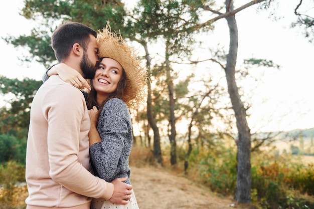 Standing and hugging Cheerful lovely young couple having a rest outdoors together