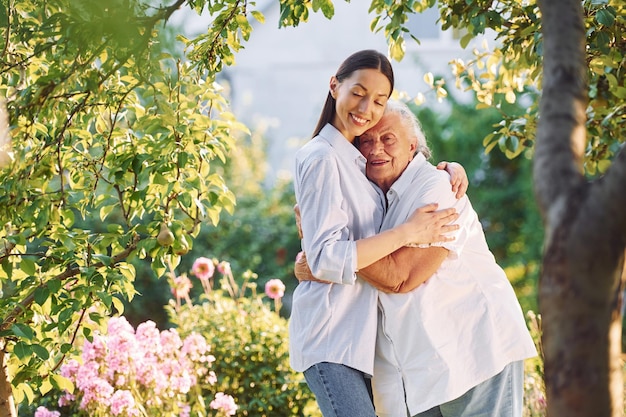 Standing together and embracing each other Young woman is with her senior mother is in the garden