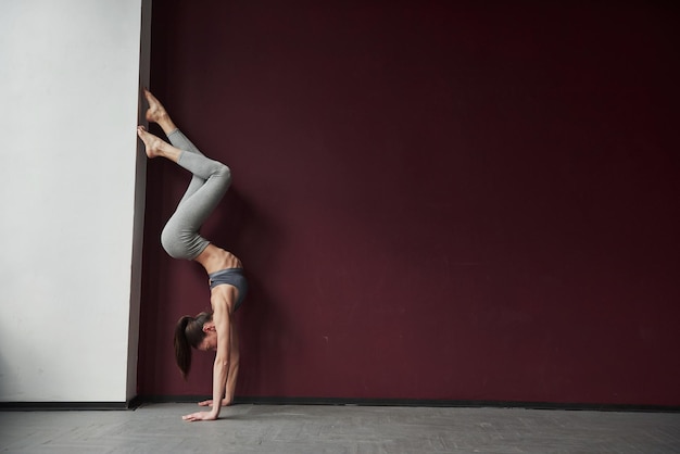 Photo stands upside down girl with good fitness body type have exercises in the spacey room