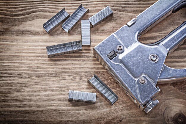 Stapler gun staples on wooden board construction concept