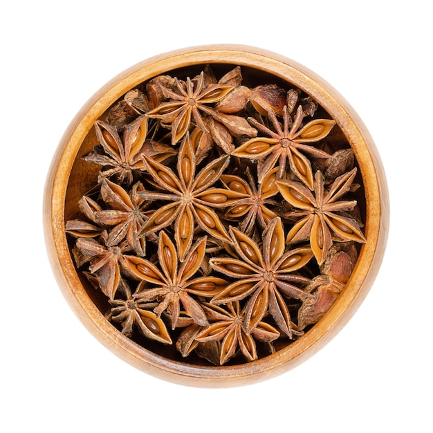 Star anise fruits and seeds in a wooden bowl