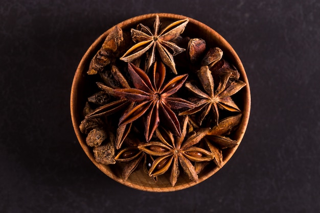 Star anise in a wooden bowl on a black table. , copyspace.