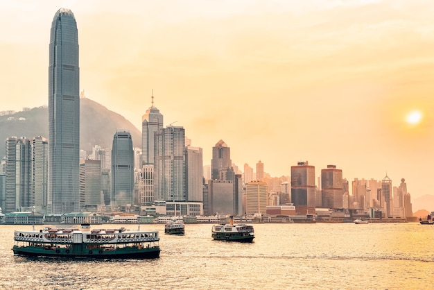 Star ferry at Victoria Harbor in HK at sundown. View from Kowloon on Hong Kong Island.