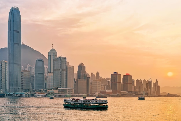 Star ferry at Victoria Harbor of Hong Kong at sunset. View from Kowloon on HK Island.