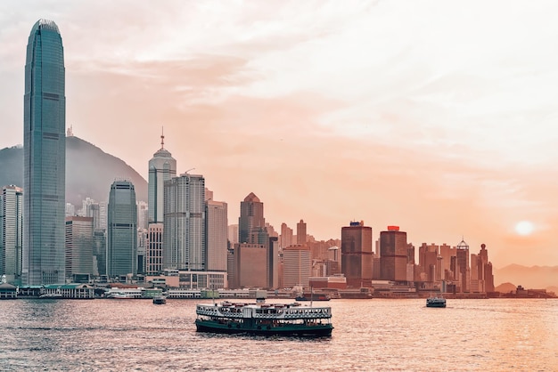 Star ferry at Victoria Harbor of Hong Kong at sunset. View from Kowloon on HK Island.