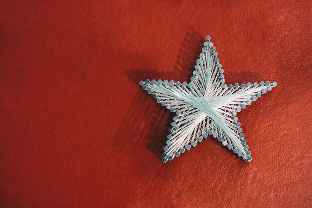 A star made from steel nails and string on red background