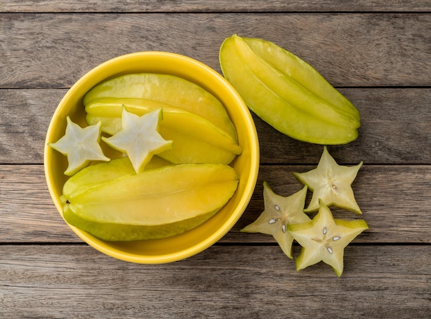 Starfruits with slices over a wooden plate