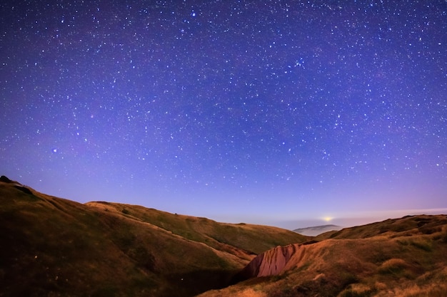 Starry night sky in the middle of world over mountains