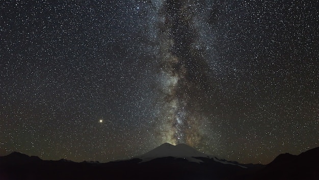 Stars of the Milky Way at night in the sky above Mount Elbrus View of the northern slope of the two peaks of the stratovolcano