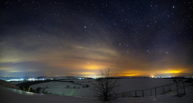 Stars of the night sky with clouds. Snowy winter landscape at dusk