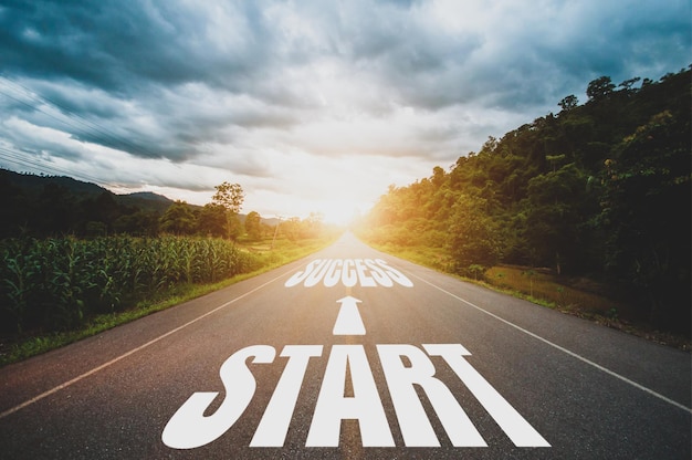 Start arrow and success text written on highway road in the middle of empty asphalt road and beautiful blue sky and sunset Starting concepts lead to success