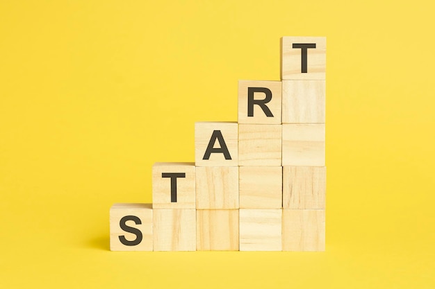 START text on wooden cubes yellow background