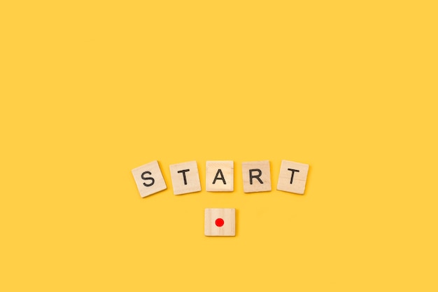 Start word write with wooden letter cubes on yellow background