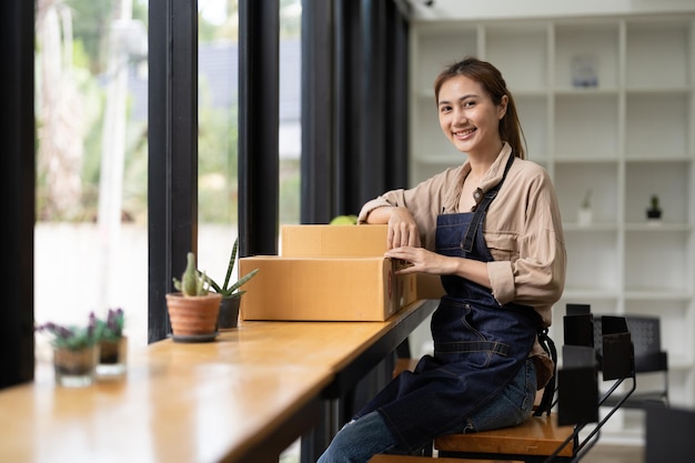 Starting a small business SME owner portrait female entrepreneur with products order online to prepare to pack a box of goods for sale to customers sme business idea