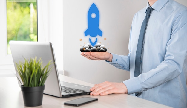 Startup business concept, Businessman holding tablet and icon rocket is launching and soar flying out from screen with network connection on dark background.