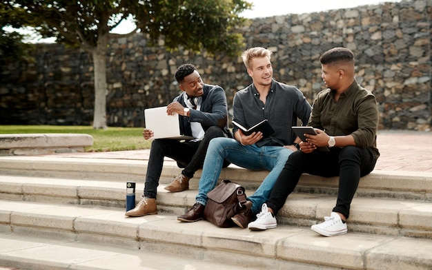 Startup entrepreneur team or friends planning business strategy with a laptop and digital tablet outdoors Diverse young and creative men in collaboration sitting and discussing project together