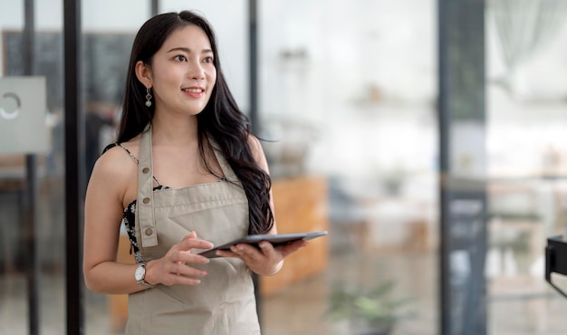 Startup successful small business owner sme beauty girl stand with tablet in coffee shop restaurant Portrait of asian woman barista cafe owner SME entrepreneur seller business concept