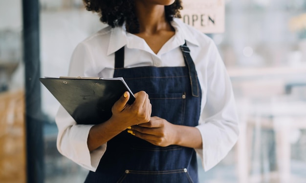 Startup successful small business owner sme beauty girl stand with tablet smartphone in coffee shop restaurant Portrait of asian tan woman barista cafe owner SME entrepreneur seller business concept