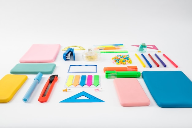 Stationary tools. Bunch of colorful bright stationary and gadget cases lying on the white surface in studio lighting