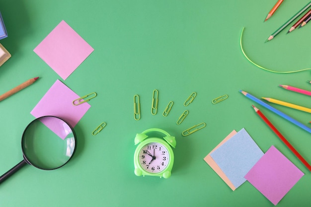 Stationery, alarm clock, books on a background of pastel colors of multi-colored paper