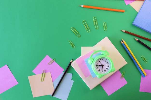 Stationery, alarm clock, books on a background of pastel colors paper, back to school, education