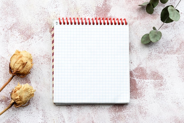 Stationery romantic delicate backgrounda clean notebook a sprig of eucalyptus and yellow roses Top view closeup and copy space