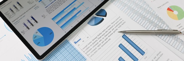 On statistical reports lies a tablet with charts on the screen