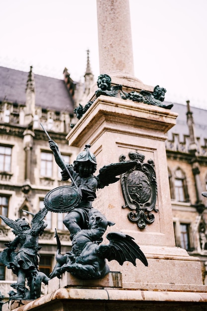 Statue of an angel defeating a snake at a column at marienplatz in munich