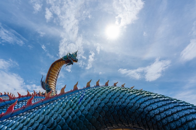 Statue of Giant Thai Naga Statue with blue sky clouds in the Phu Manorom Temple at Mukdahan Provinc