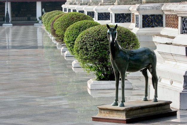 A statue of a horse stands and watches the people in the temple.