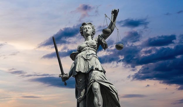 The Statue of Justice - lady justice or Iustitia against sunset sky with clouds. ideal for websites and magazines layouts