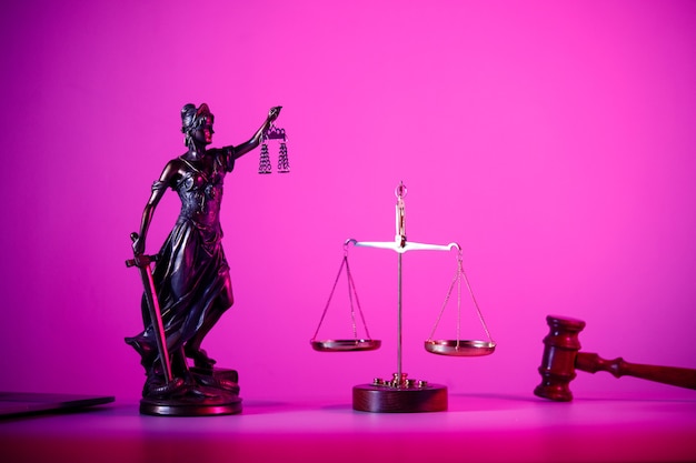 Statue of Lady Justice with scales on the table in purple neon.