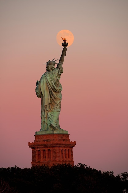 Statue of Liberty and full moon at sunset in New York City