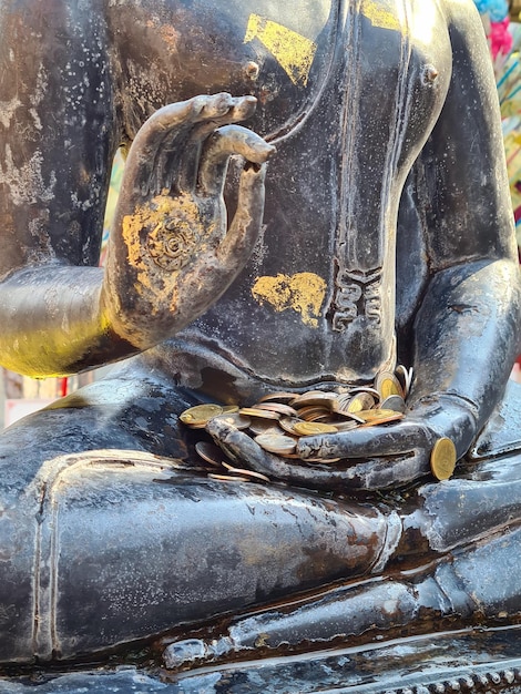 statue of manyfaced Buddha with donations of coins in a Thai temple