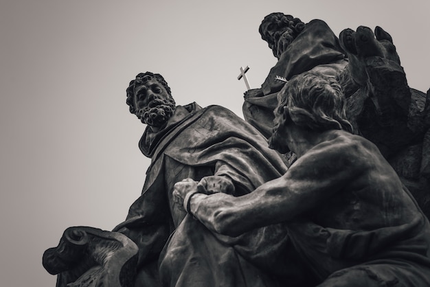 Photo statue of saints john of matha, feliz of valois, and ivan on charles bridge. prague, czech