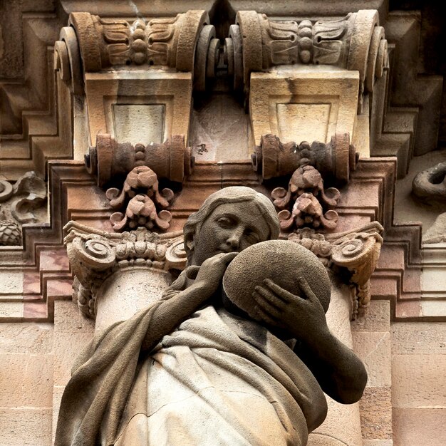 Photo a statue of a woman holding a ball in front of a building.